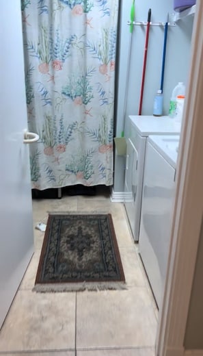 Een badkamer met douchegordijn, vloerkleed en toilet.