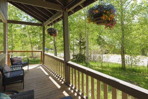 A covered porch with outdoor furniture and hanging flower baskets.