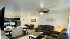 A modern living room with a sofa, coffee table, and a dining area with chairs and a table. - 3 bedroom house with AC in charming Kingman Near The Hospital Top restaurants (Kingman)