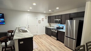 A modern kitchen with dark cabinets, stainless steel appliances, a marble countertop island, and recessed ceiling lights. - 3 bedroom house with AC in charming Kingman Near The Hospital Top restaurants (Kingman)