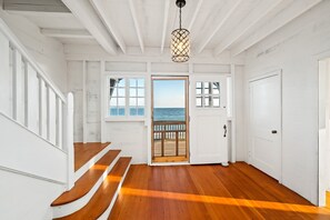 Una escalera de madera que lleva a una puerta con vista al mar.