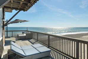 Una terraza de madera con mobiliario exterior y vistas a la playa.