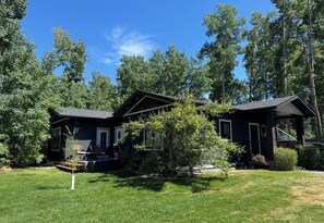 A two-story house with a dark exterior, a front porch, and a well-maintained lawn.