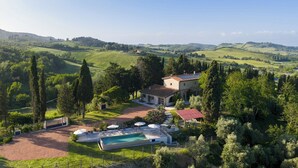 Eine Villa mit Swimmingpool, umgeben von üppiger Vegetation und Hügeln.