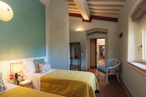 A hotel room with two beds, a chair, a lamp, and a view of the hallway. - Il Poggione 10, Emma Villas (Crocino)