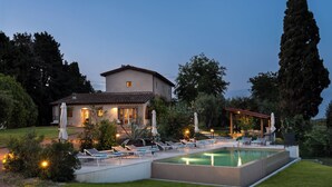 Ein Haus mit Schwimmbad, Liegestühlen und einer Pergola.