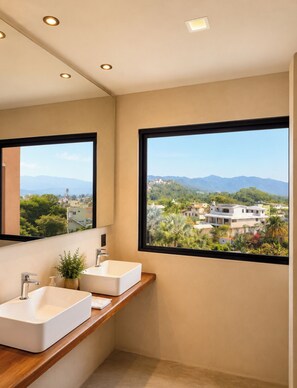 Ein Badezimmer mit zwei Waschbecken, einem Spiegel und einem Fenster mit Blick auf eine Stadtlandschaft und Berge.