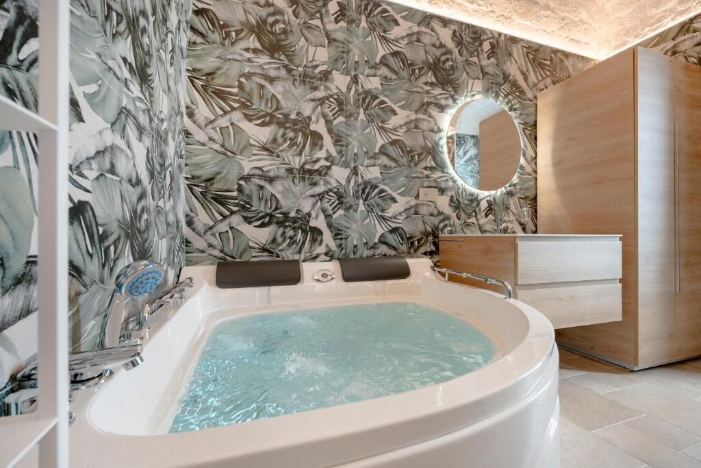 Une salle de bain avec un jacuzzi, un meuble-lavabo en bois et un miroir.