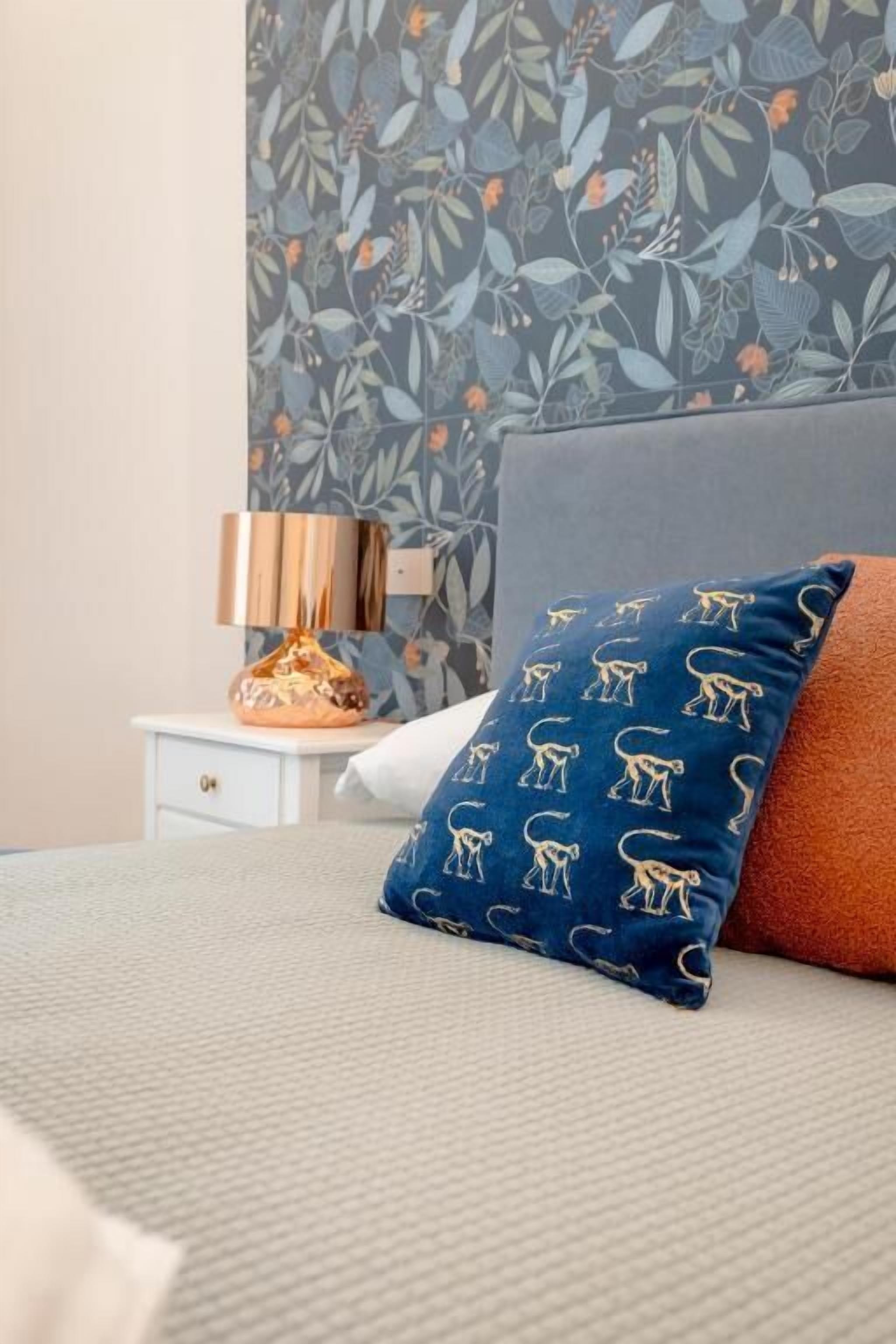 Ein Bett mit einem blauen, einem weißen und einem orangefarbenen Kissen.