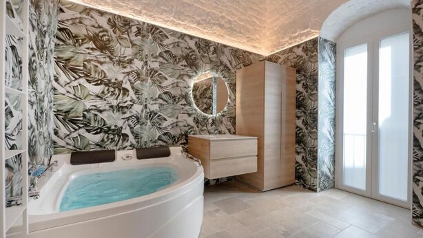 Un bagno con una grande vasca da bagno, un mobile bagno in legno, uno specchio e una porta con pannelli in vetro smerigliato.