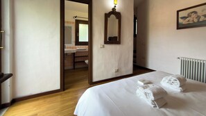 Ein Hotelzimmer mit Bett, offenem Türrahmen zum Badezimmer, Spiegel und Heizkörper.
