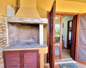 A kitchen with a built-in oven, a stone backsplash, and a sliding glass door leading to an outdoor area. - Villa Margherita - 200m from beach Costa Rei (Costa Rei)