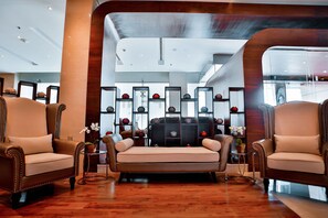 Un hall d’entrée moderne avec des fauteuils en cuir, un canapé et un mur décoratif agrément é d’étagères.