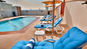 A rooftop pool area with lounge chairs and a ladder.