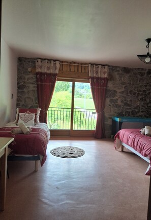 Ein Schlafzimmer mit zwei Betten, einer Steinsäule, einem Balkon mit Geländer und einem Deckenventilator.