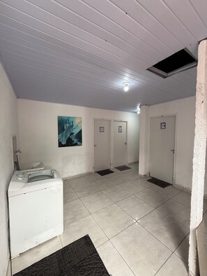 Een wasruimte met een wasmachine, een droogrek en een schilderij aan de muur.