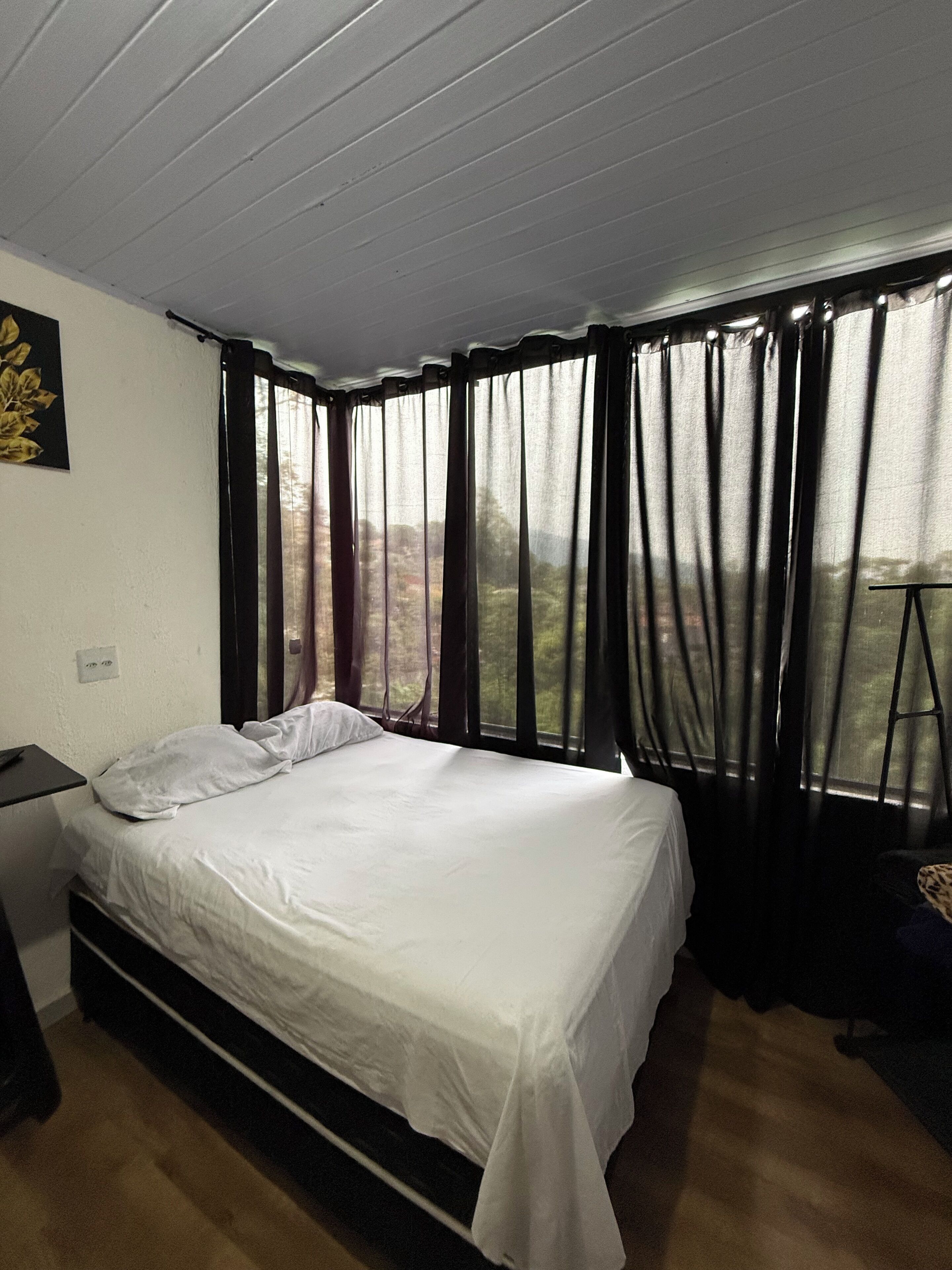 Une chambre à coucher avec un lit, un bureau, une chaise et une fenêtre avec des rideaux.