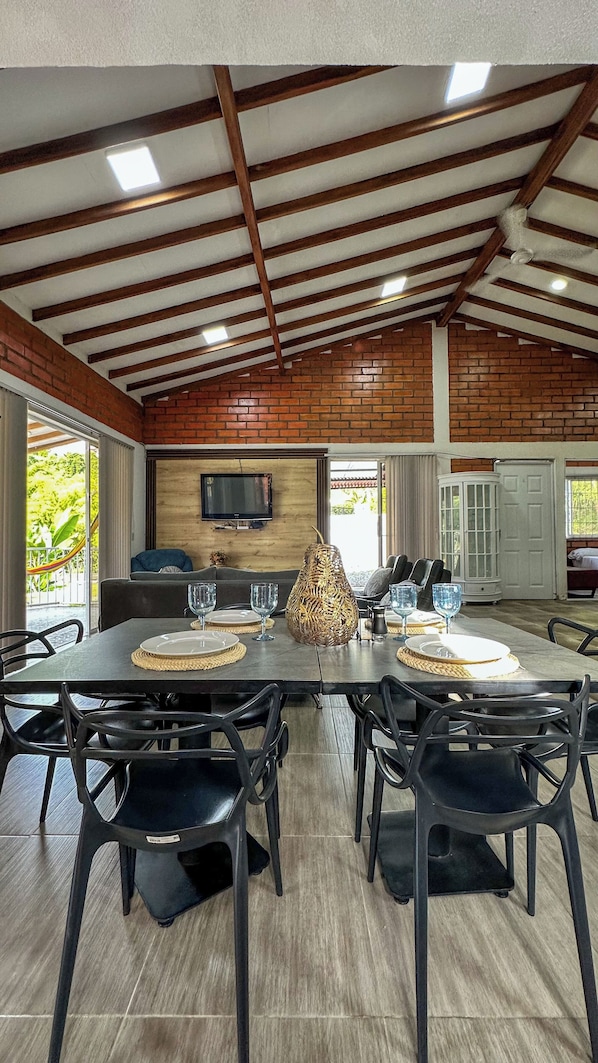 Un espace repas avec une longue table, des chaises noires et une décoration centrale faite d’un objet tressé.