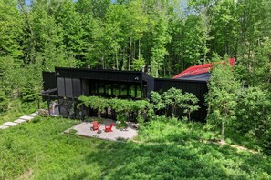 Ein modernes Haus mit schwarzem Anstrich, umgeben von dichtem Wald.