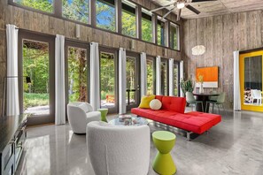 A spacious room with large windows, a red sofa, white chairs, and a dining area. - Midnight Hollow in Fennville (Fennville)