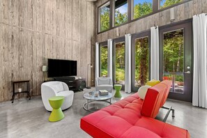 A modern living room with a large flat-screen TV, a red sofa, a white armchair, and a green coffee table. - Midnight Hollow in Fennville (Fennville)