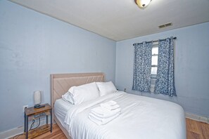 Une chambre à coucher avec un lit, une table de chevet avec une lampe et une fenêtre ornée de rideaux à motifs.