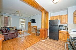 A living room with a leather sofa, a fireplace, a TV, and wooden flooring. - Comfy & Convenient 2-Bed Fl 1 Apt @DowntownAlbany (Albany)