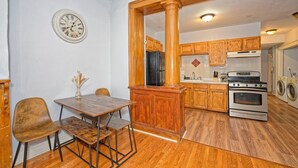 A kitchen with wooden cabinets, a refrigerator, an oven, and a dining area with a table and chairs.