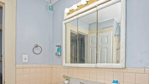 A bathroom with a sink, vanity, mirror, and towel ring.