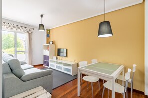 Una sala de estar moderna con un sofá, una mesa de comedor, sillas, un televisor y una estantería.