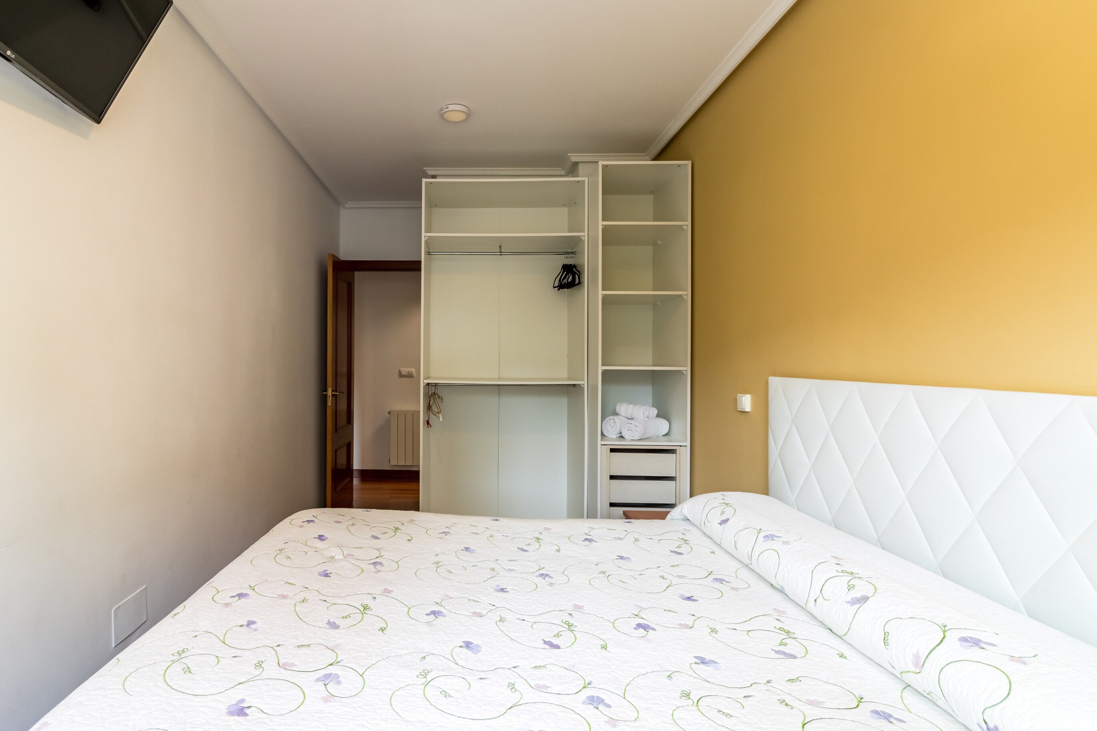 A bedroom with a bed, a wardrobe, and a television.