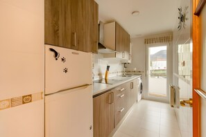 Una cocina con armarios de madera, un refrigerador, un lavamanos y un ventanal con vistas.