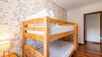 Una cama litera con estructura de madera, una pared con diseño y una mesita de noche con lámpara.