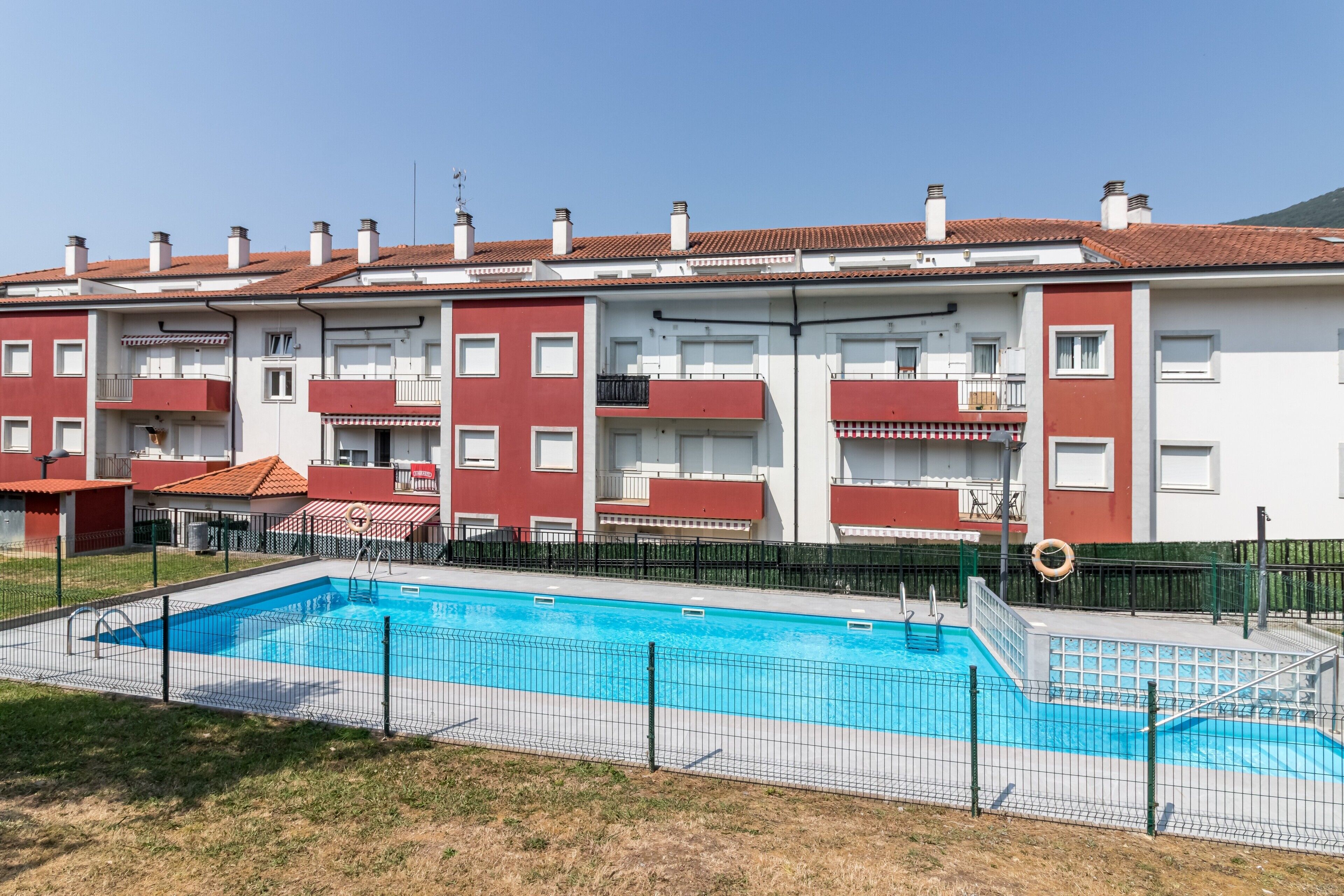 Un edificio residencial con piscina, balcones y cielo despejado.