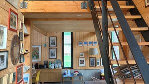 Un interior de madera con un dormitorio en el altillo, una escalera y un comedor.