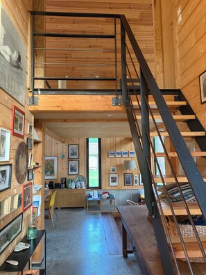 Ein Holzinnenraum mit Schlafzimmer auf dem Dachboden, einer Treppe und einem Essbereich.