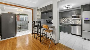Una cucina moderna con mobili grigi, elettrodomestici in acciaio inossidabile e pavimento in legno.