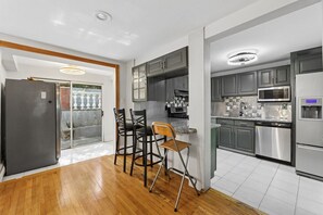 A modern kitchen with grey cabinets, stainless steel appliances, and a wooden floor. - Beautiful 3 bedroom house minutes from NYC, Metlife, & American Dream Mall (Teaneck)