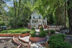 A two-story house with a front porch, surrounded by a brick garden and trees. - Beautiful 3 bedroom house minutes from NYC, Metlife, & American Dream Mall (Teaneck)