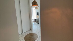 En hall med en golvlampa och en matta, båda tillverkade av vävt material, samt en dörr som leder till ett annat rum.