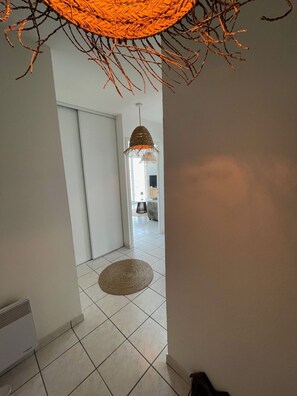 Ein Flur mit einer gewebten Stehlampe, einem gewebten Teppich und einer Tür zu einem anderen Raum.