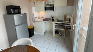 Ett kompakt kök med kylskåp, mikrovågsugn och en hängande lampa.