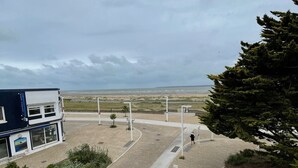 En asfalterad gångväg leder fram till en byggnad med utsikt över stranden.