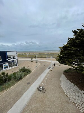 Ein gepflasterter Weg führt zu einem Gebäude mit Blick auf den Strand.