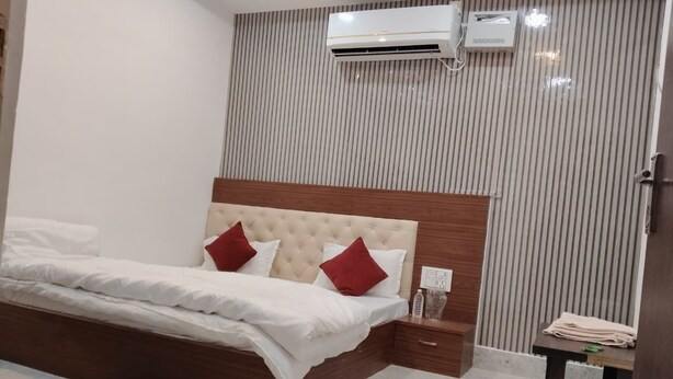 Quarto com cama, mesa de cabeceira, ar condicionado fixado na parede e parede listrada.