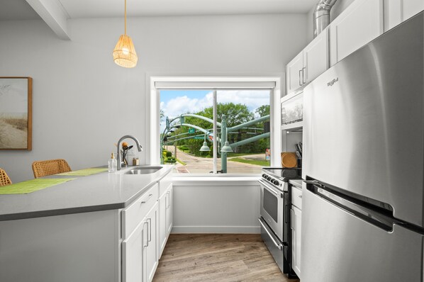 Een moderne keuken met een roestvrijstalen koelkast, een raam met uitzicht op een park en een hangende吊灯.