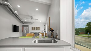 A modern kitchen with a large window, a built-in sink, and a ceiling fan.