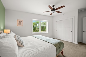 Une chambre à coucher avec un lit, un ventilateur de plafond, une fenêtre et une porte.