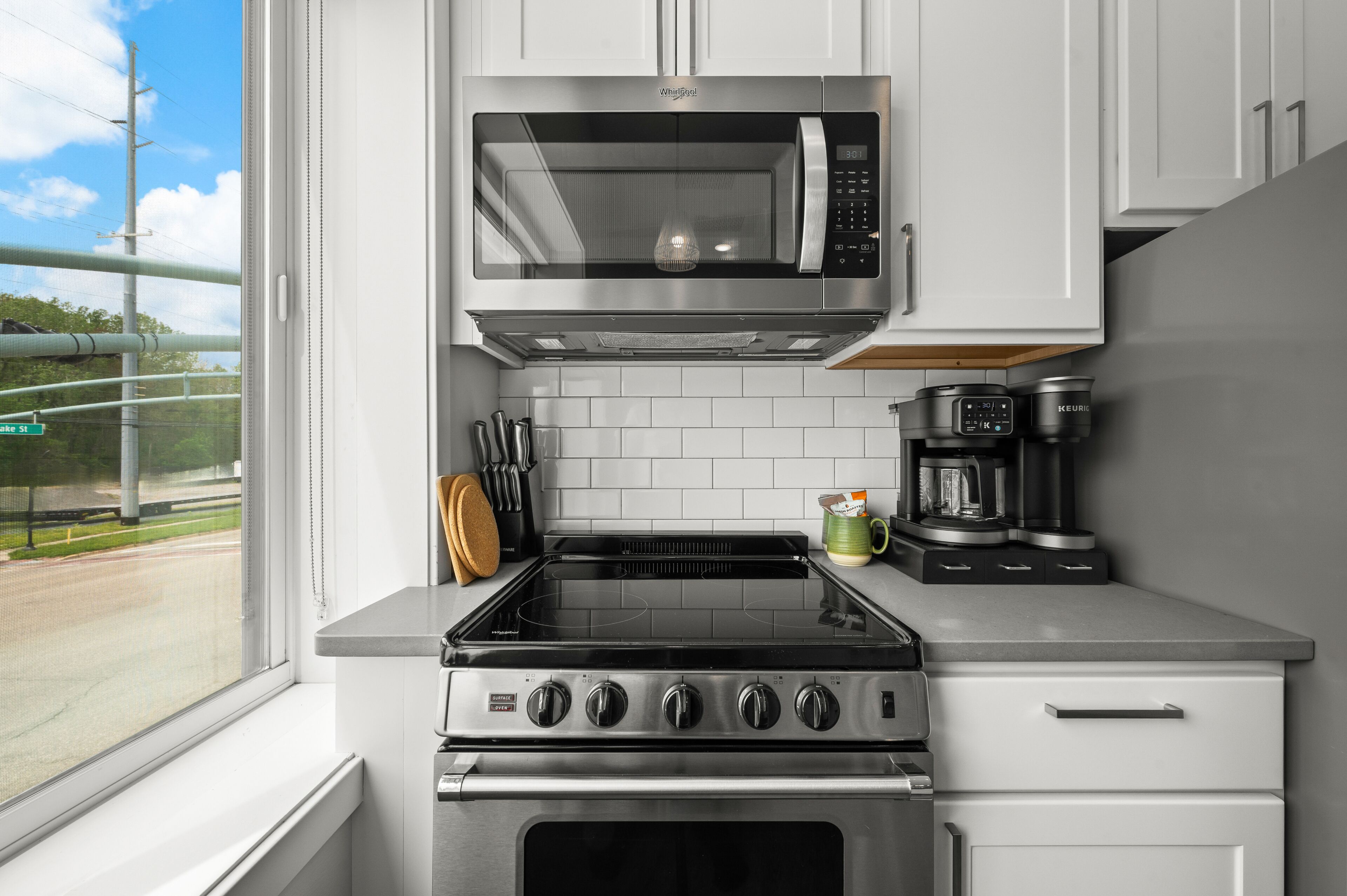 A kitchen with a microwave, stove, and coffee maker.