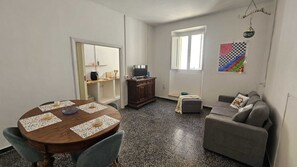 A compact living space with a dining table, a sofa, a television, and a window.